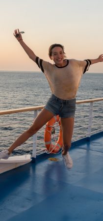 Happy girl on a ferry transfer in Crete with the blue sea at the background