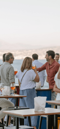 People enjoy drinks and seaview at a villa party