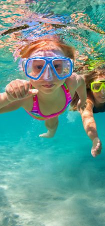 Girl and mother dive into the blue seas waters